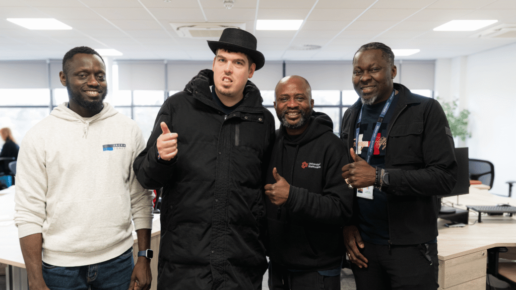 Alex stands confidently alongside his support workers, smiling and engaging together in a supportive environment.