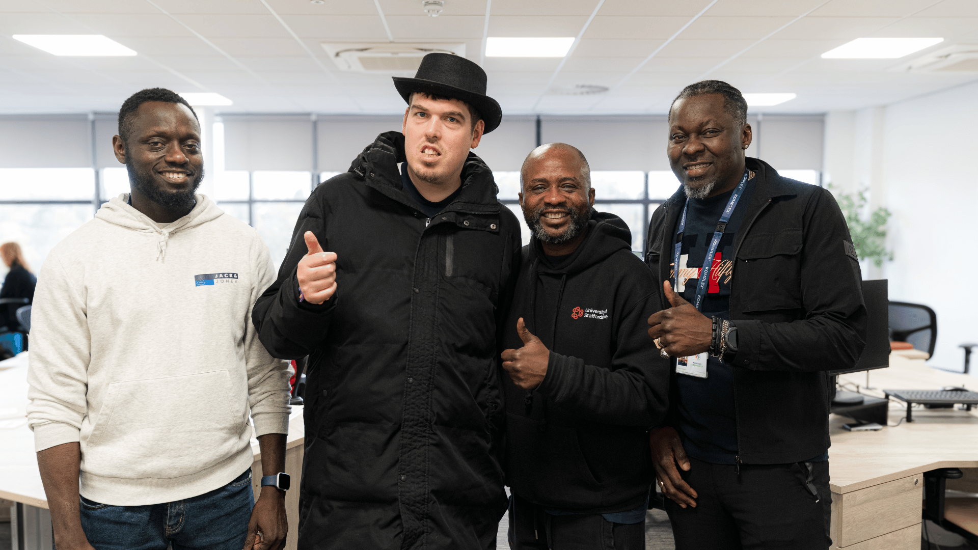 Alex stands confidently alongside his support workers, smiling and engaging together in a supportive environment.